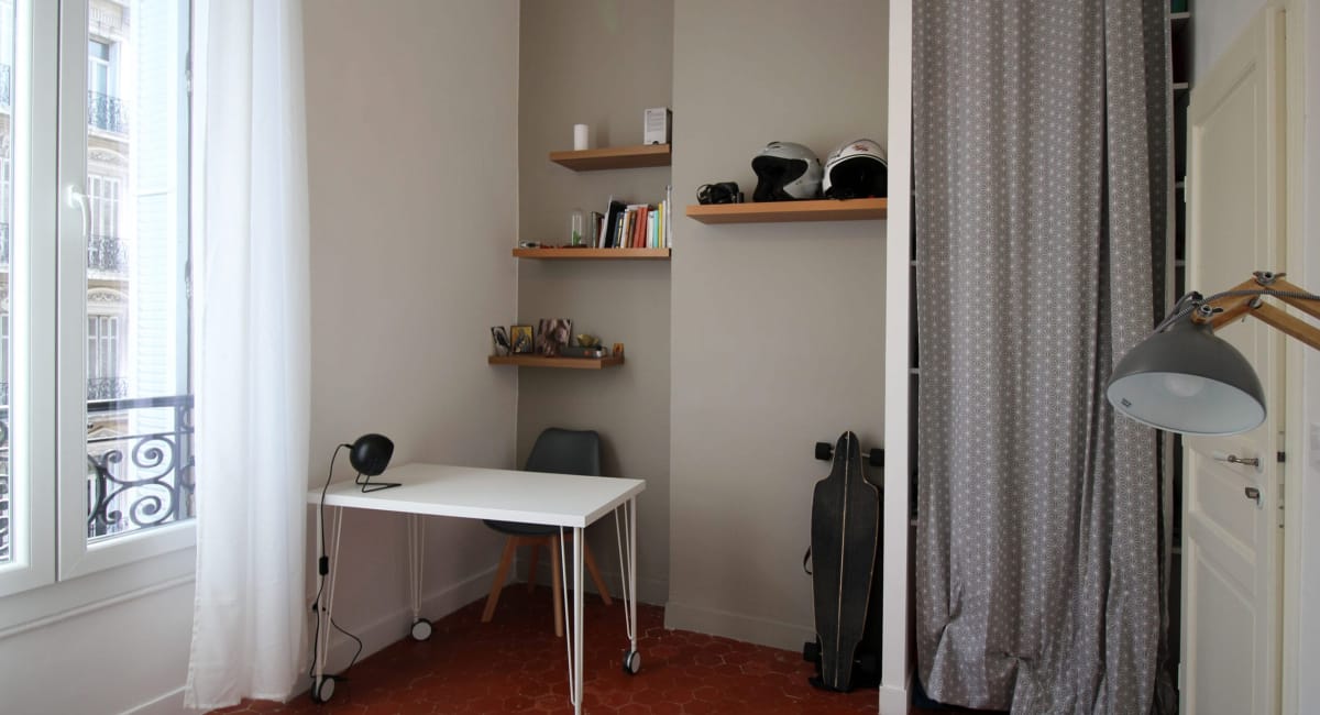 Petit bureau avec étagères et rideau dans une chambre cosy.