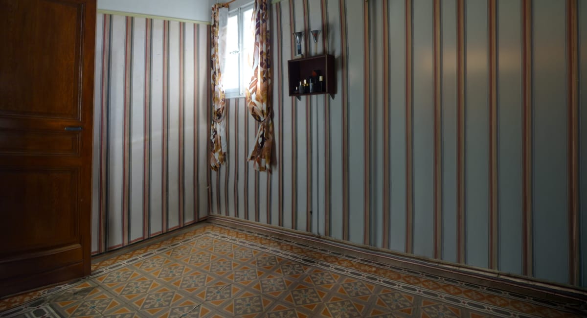 Une pièce avec un papier peint rayé et un sol décoré, ambiance vintage et chaleureuse.