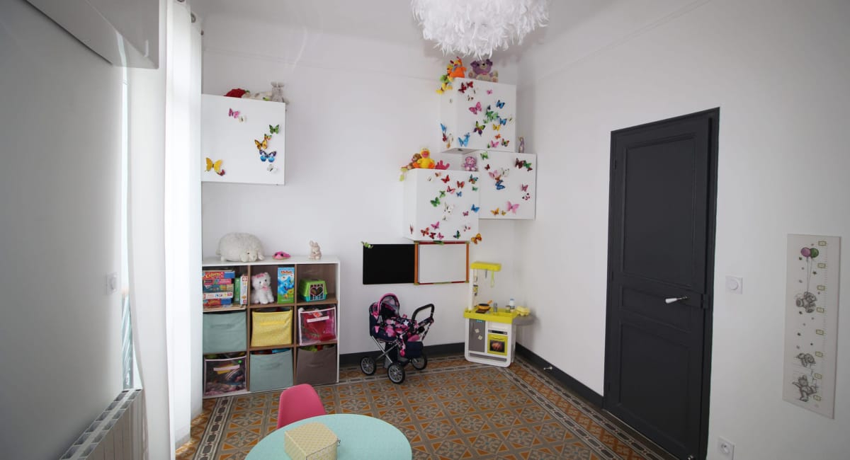 Une chambre d'enfant colorée et joyeuse, décorée de papillons et remplie de jouets.