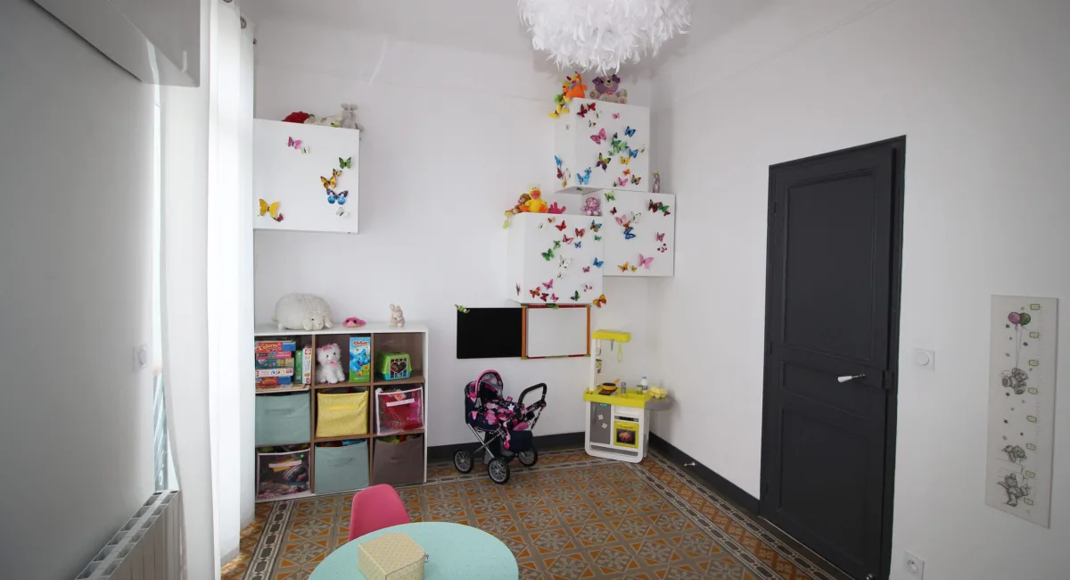 Une chambre d'enfant colorée et joyeuse, décorée de papillons et remplie de jouets.