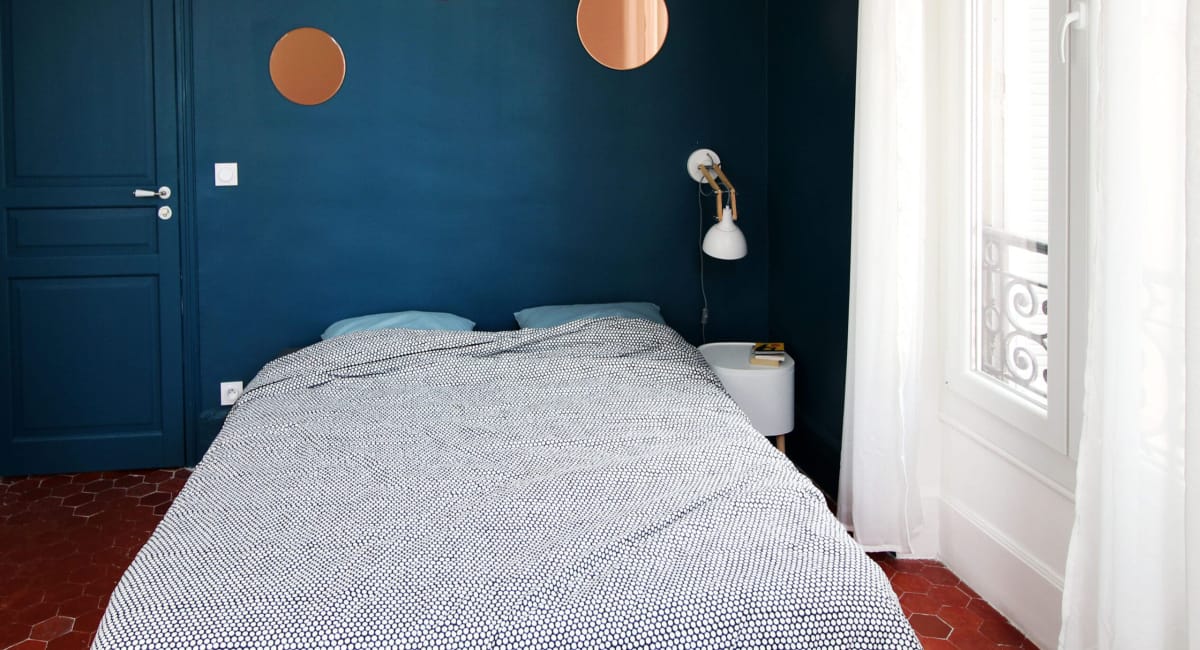 Une chambre bleu foncé avec un lit blanc et des décorations rondes.