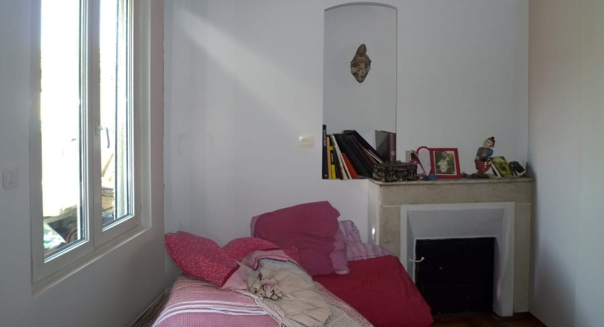 Coin d'une chambre avec une fenêtre, un canapé et une cheminée décorée.