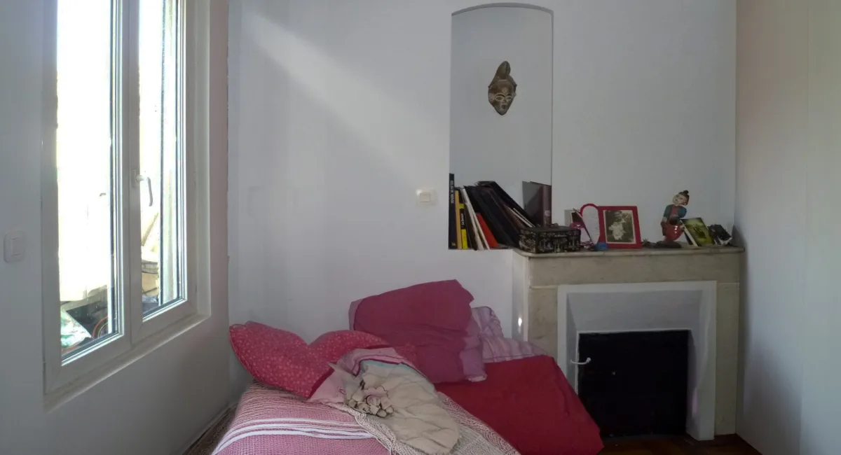 Coin d'une chambre avec une fenêtre, un canapé et une cheminée décorée.