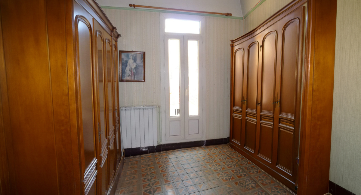 Dégagement d'une entrée avec armoires en bois et radiateur, style ancien.