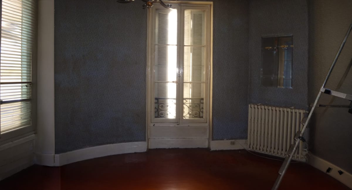 Une pièce avec un mur bleu, une fenêtre double et un radiateur.