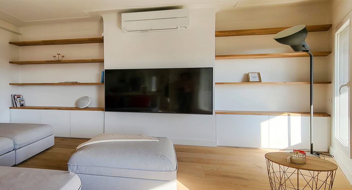 Salon moderne avec étagères, téléviseur et canapé confortable, ambiance chaleureuse.