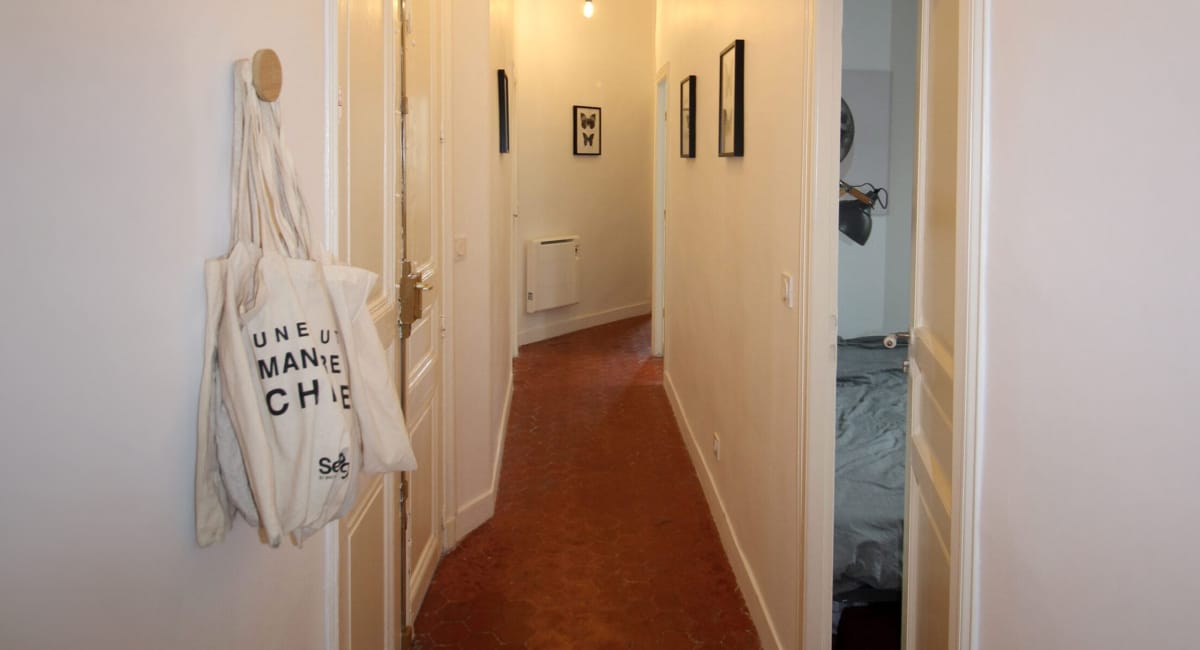 Un couloir intérieur d'une maison avec un sac suspendu et une vue sur une chambre.