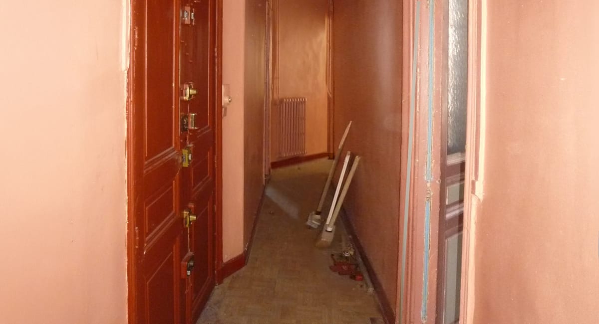 Un couloir beige avec des portes rouges et des outils de bricolage.