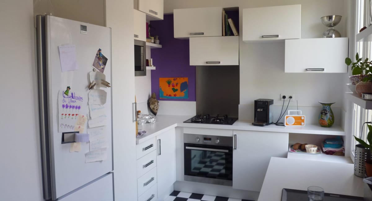 Cuisine moderne et lumineuse avec des armoires blanches et un sol noir et blanc.