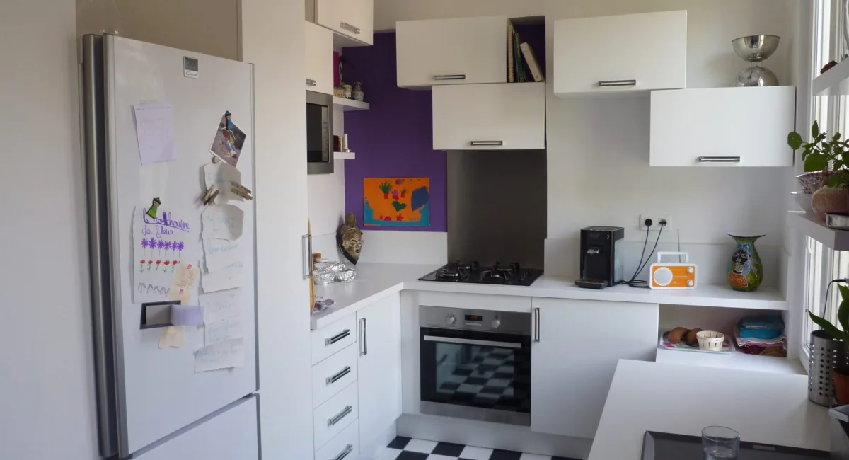Cuisine moderne et lumineuse avec des armoires blanches et un sol noir et blanc.
