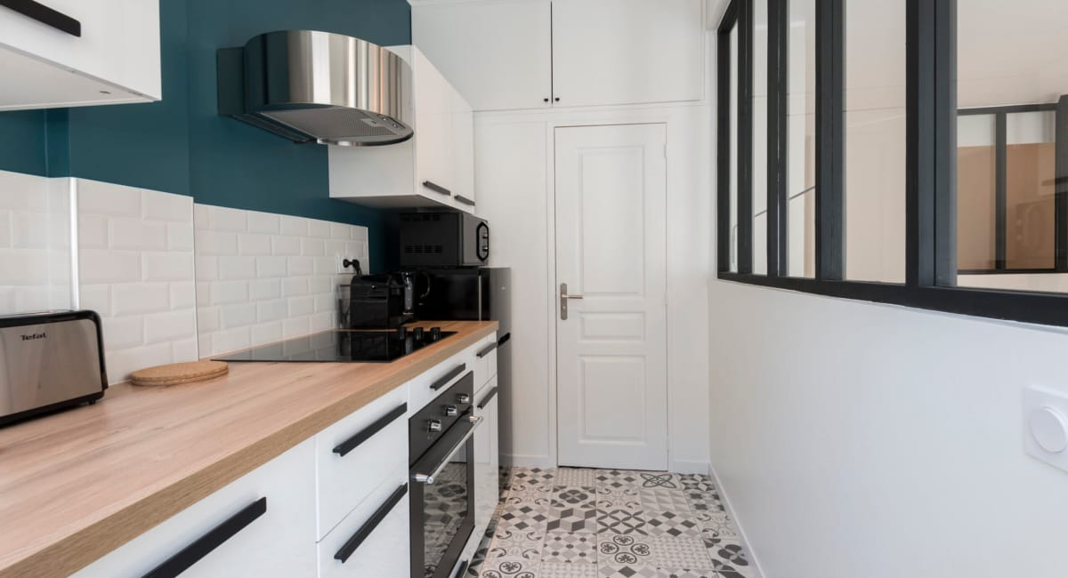 Cuisine moderne et lumineuse avec des équipements blancs et des touches de bleu.