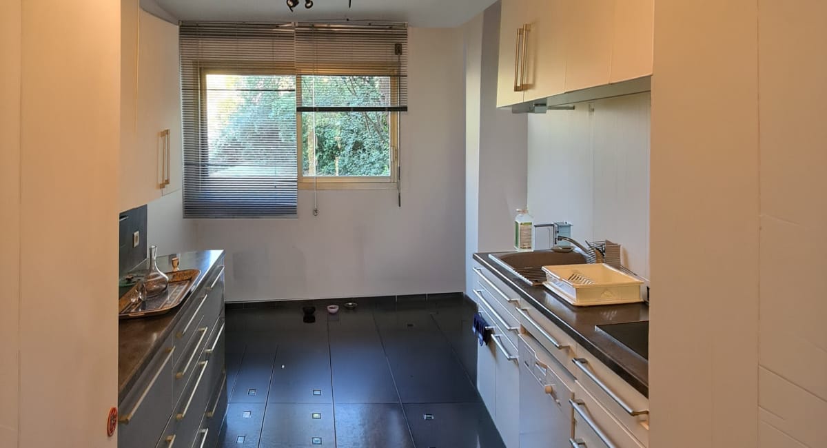 Cuisine moderne et fonctionnelle avec des armoires blanches et un sol noir.