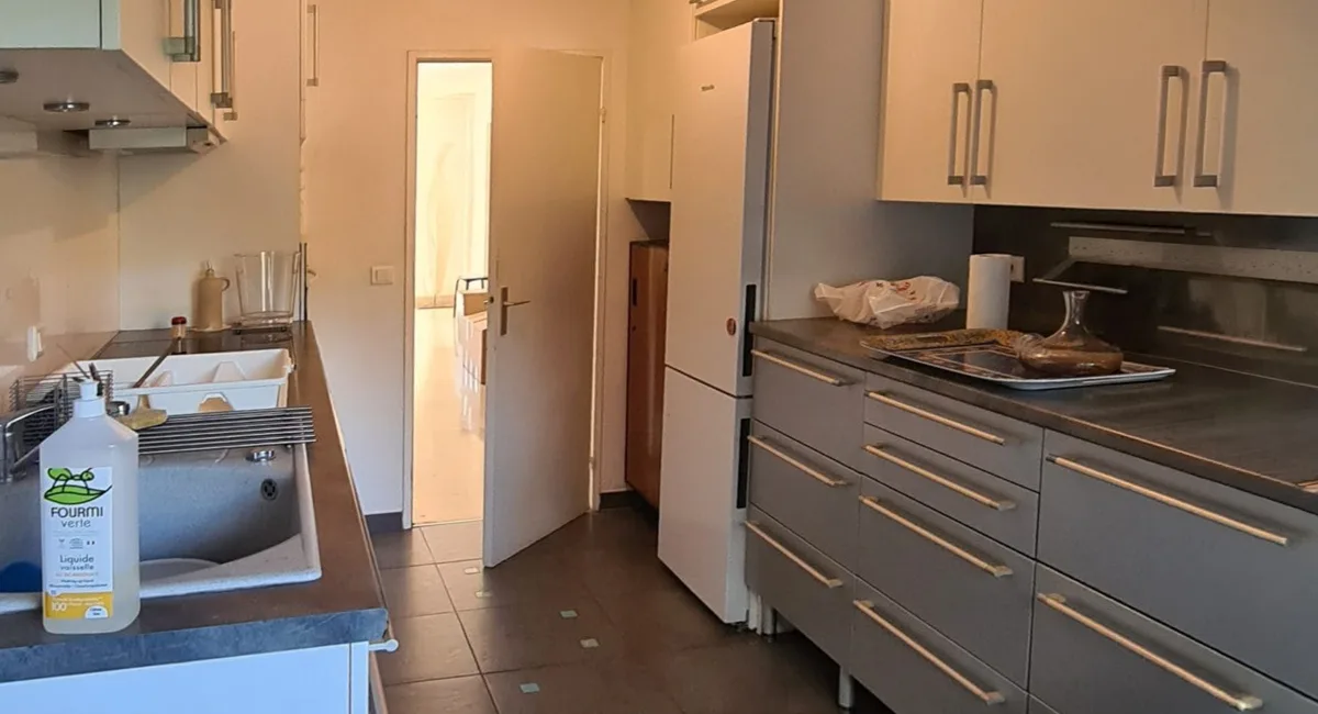 Cuisine moderne avec un évier, une crédence blanche et des armoires en bois clair.