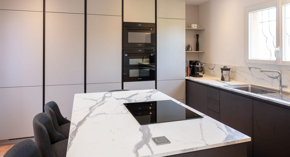 Cuisine moderne et élégante avec un îlot central en marbre blanc et des armoires grises.