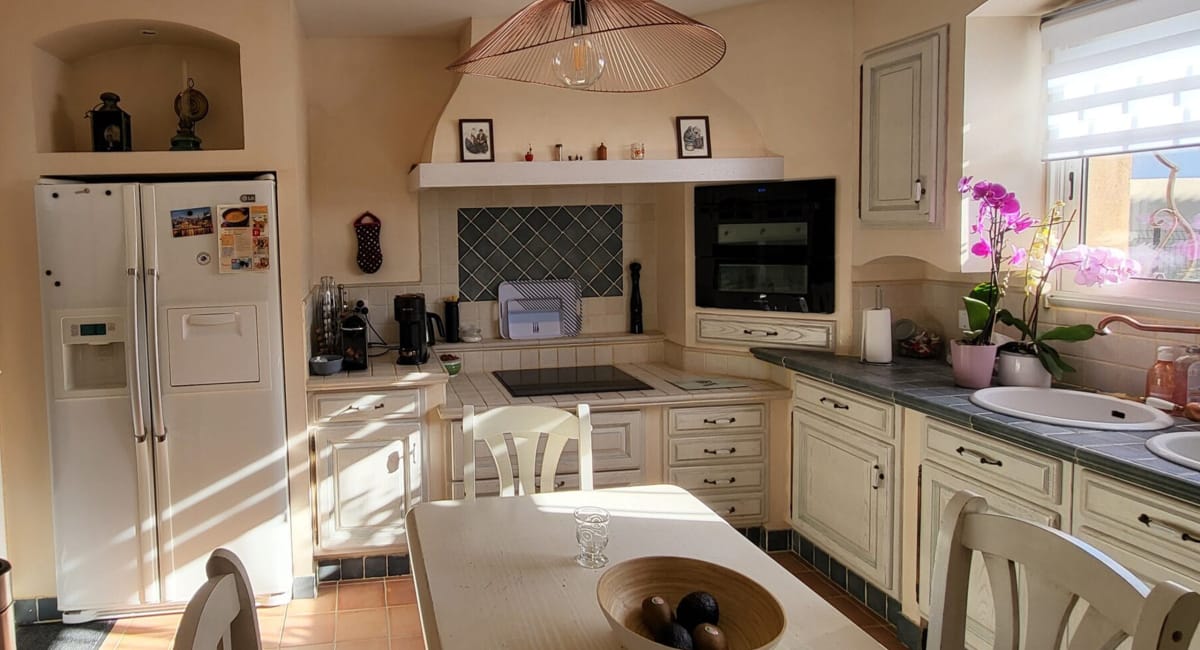 Cuisine chaleureuse et lumineuse avec des armoires blanches et un décor rustique.