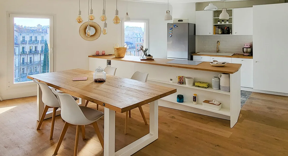 Cuisine moderne et lumineuse avec une grande table en bois et îlot central.