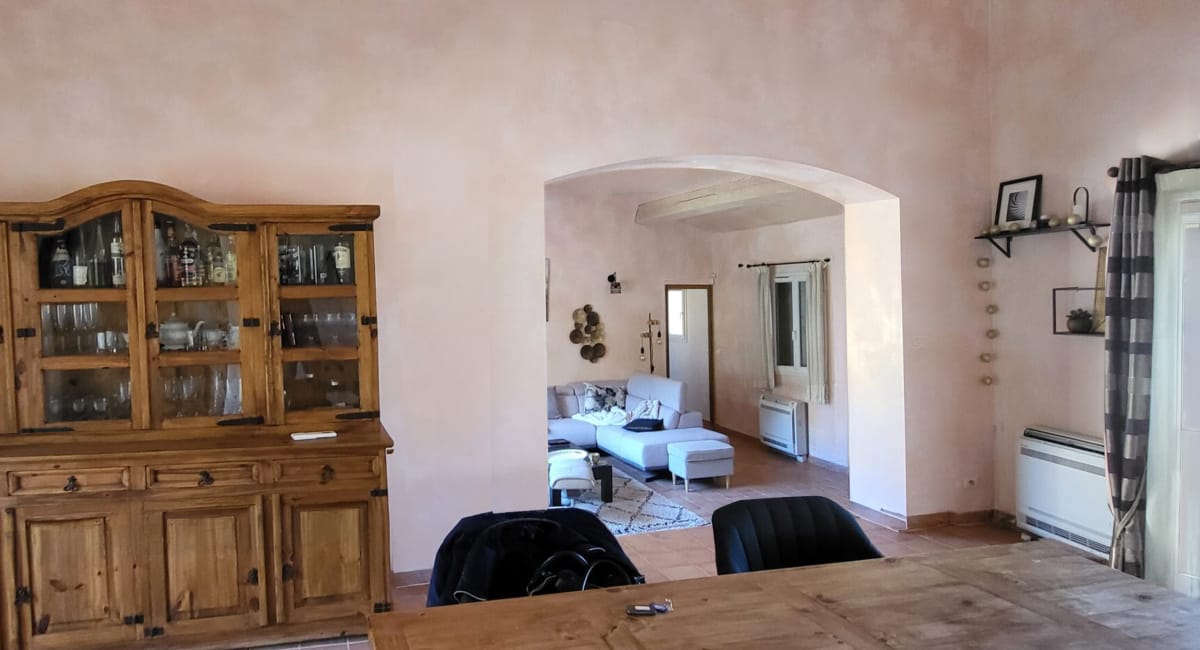 Vue d'un salon et d'une salle à manger reliés par un arc.