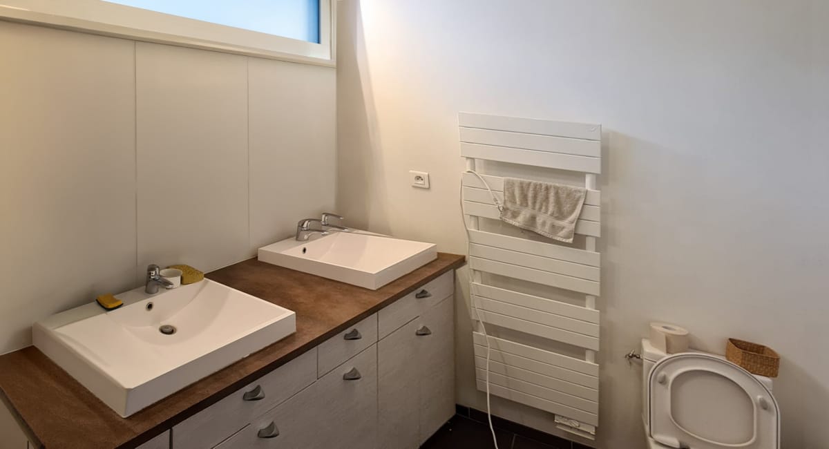 Salle de bain simple avec lavabo, radiateur à serviettes et toilettes blanches.