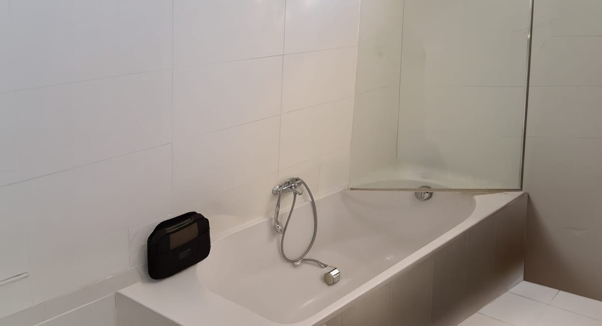 Baignoire blanche avec miroir et carrelage dans une salle de bain moderne.