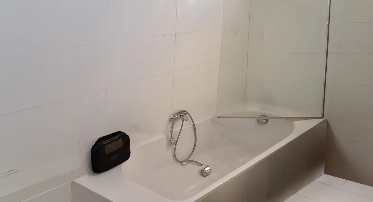 Baignoire blanche avec miroir et carrelage dans une salle de bain moderne.