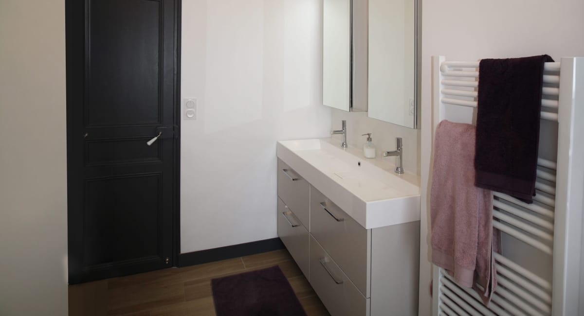 Une salle de bain moderne avec un lavabo double, un miroir et un radiateur à serviettes.