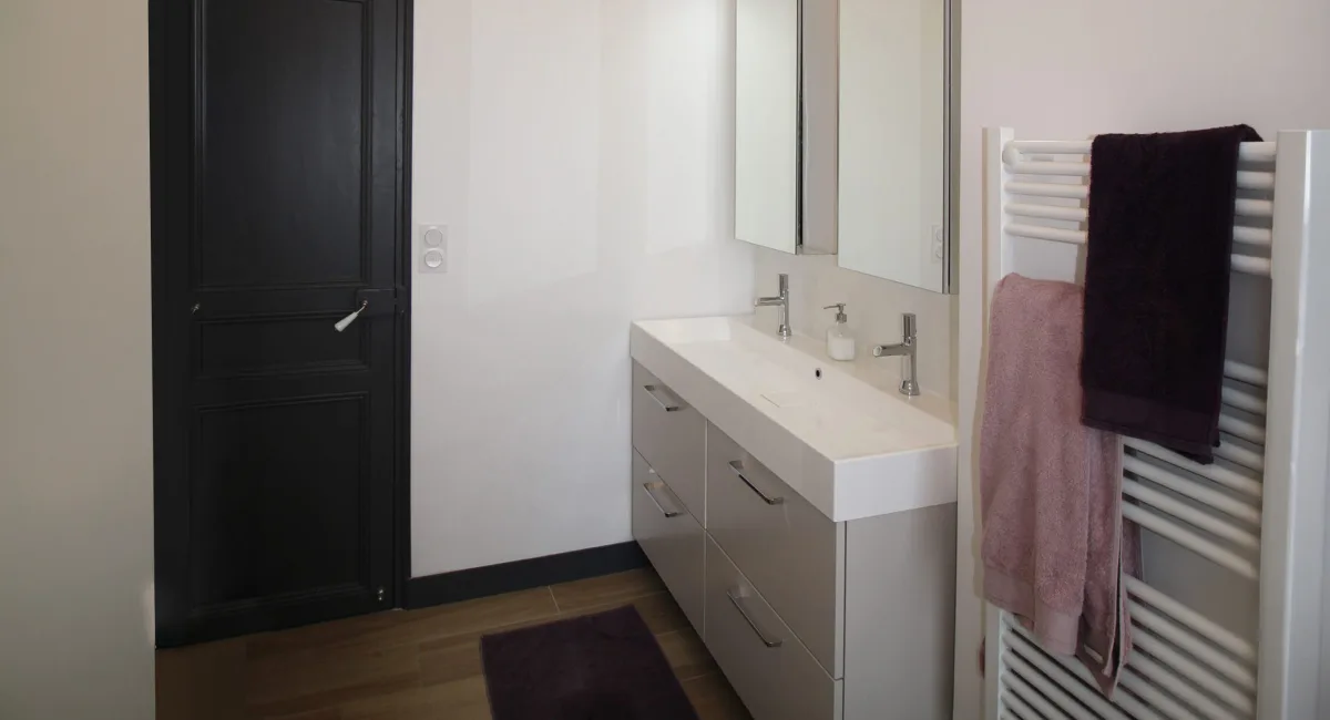 Une salle de bain moderne avec un lavabo double, un miroir et un radiateur à serviettes.