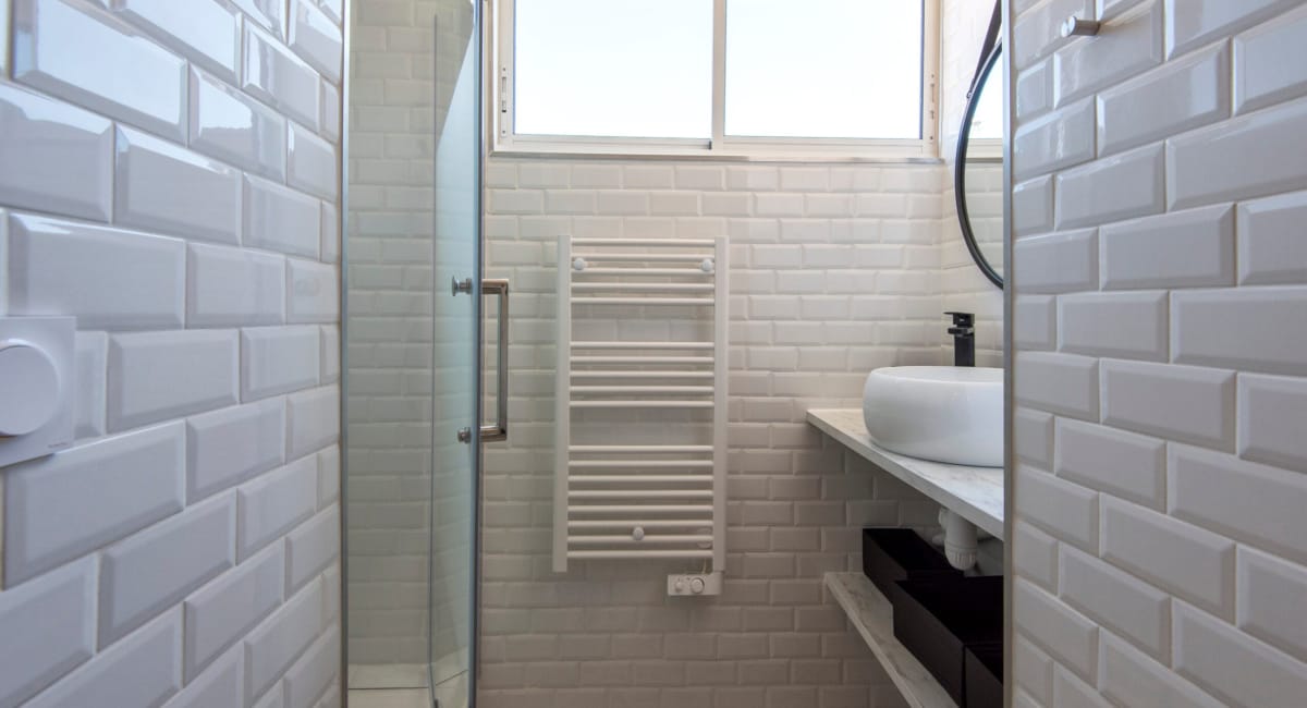 Salle de bain moderne avec carrelage blanc, douche et radiateur à simple effet.