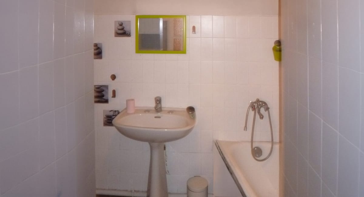 Salle de bain simple avec lavabo, miroir et baignoire, décorée de motifs décoratifs.