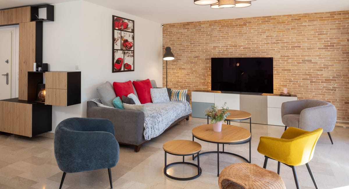 Salon moderne et chaleureux avec canapé, murs en briques et décoration colorée.