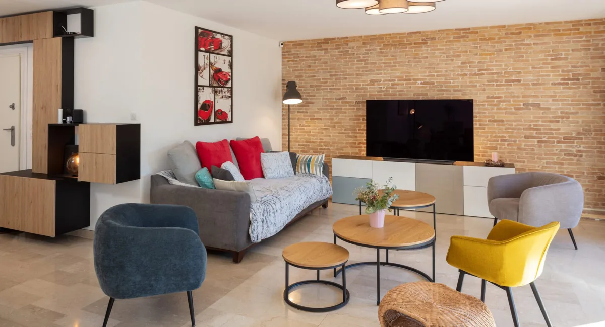 Salon moderne et chaleureux avec canapé, murs en briques et décoration colorée.