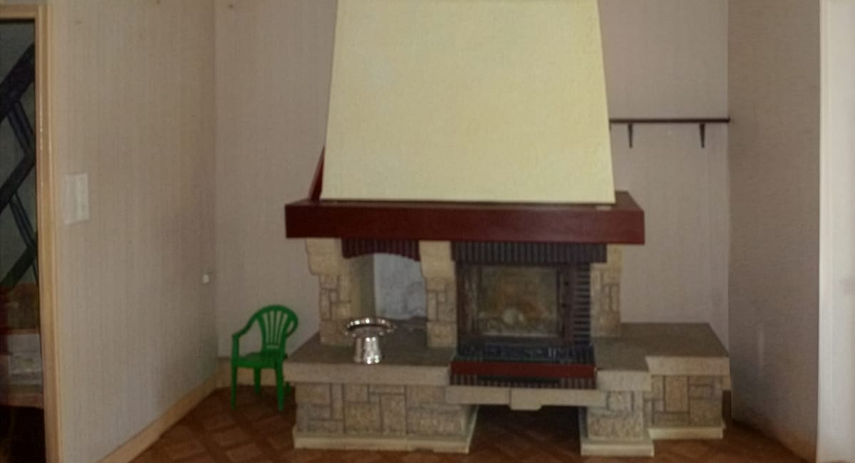 Cheminée en pierre décorative dans un salon, avec un haut fourneau blanc et un siège vert.
