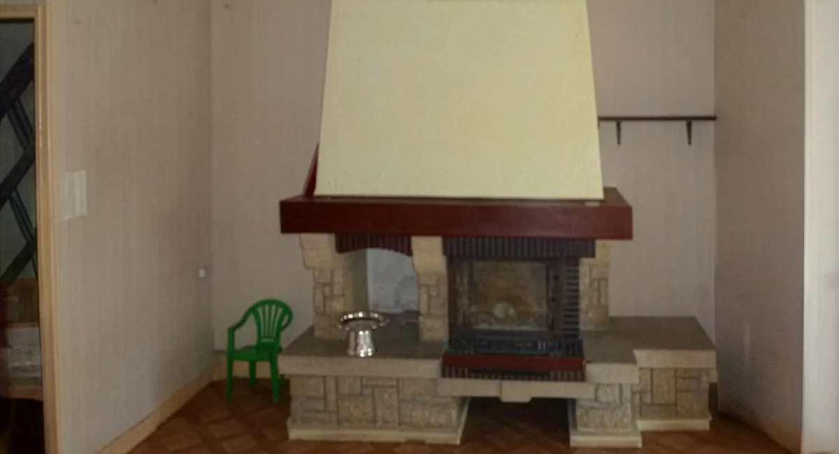 Cheminée en pierre décorative dans un salon, avec un haut fourneau blanc et un siège vert.