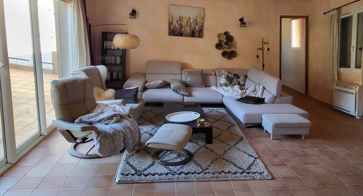 Salon cosy avec canapé d'angle, tapis et décoration chaleureuse.