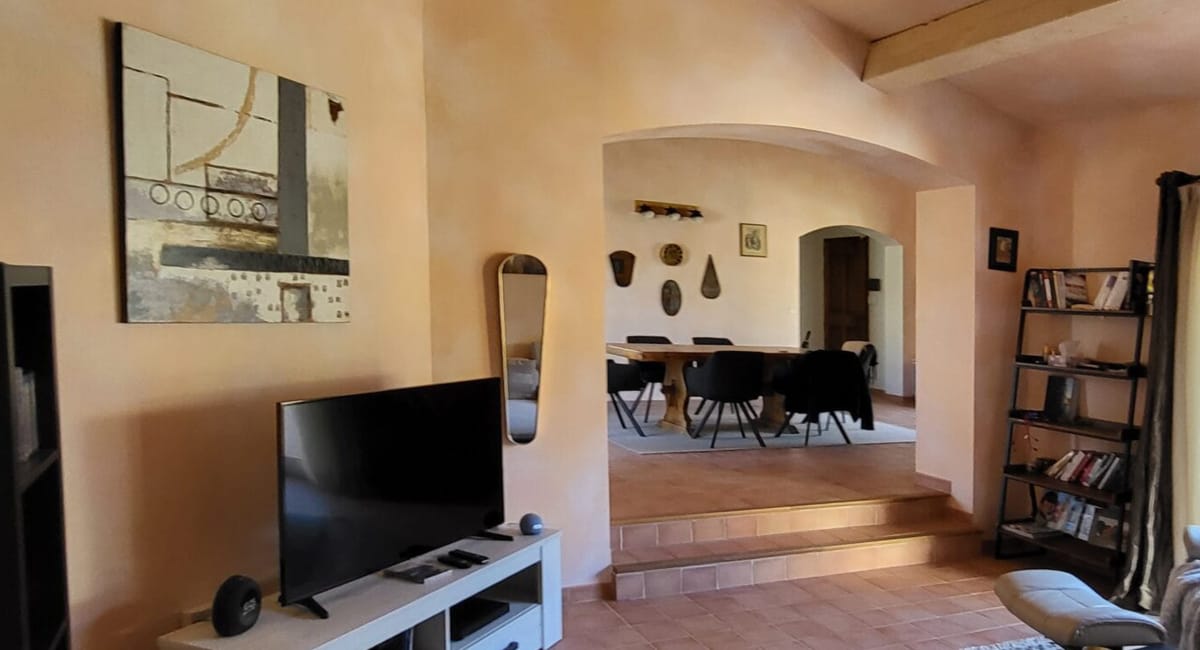 Intérieur d'une pièce avec un téléviseur, une œuvre d'art et un accès à un espace repas.