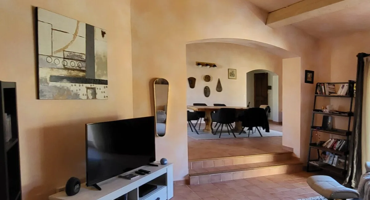 Intérieur d'une pièce avec un téléviseur, une œuvre d'art et un accès à un espace repas.