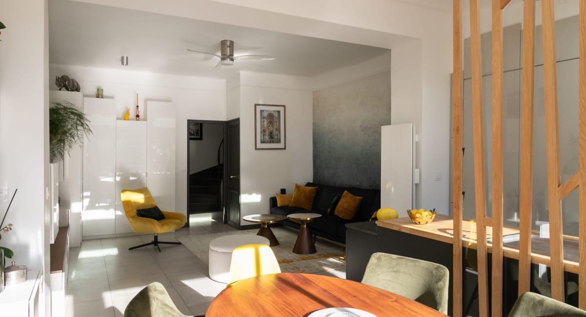 Intérieur moderne et lumineux d'un salon avec canapé, fauteuil et décoration colorée.