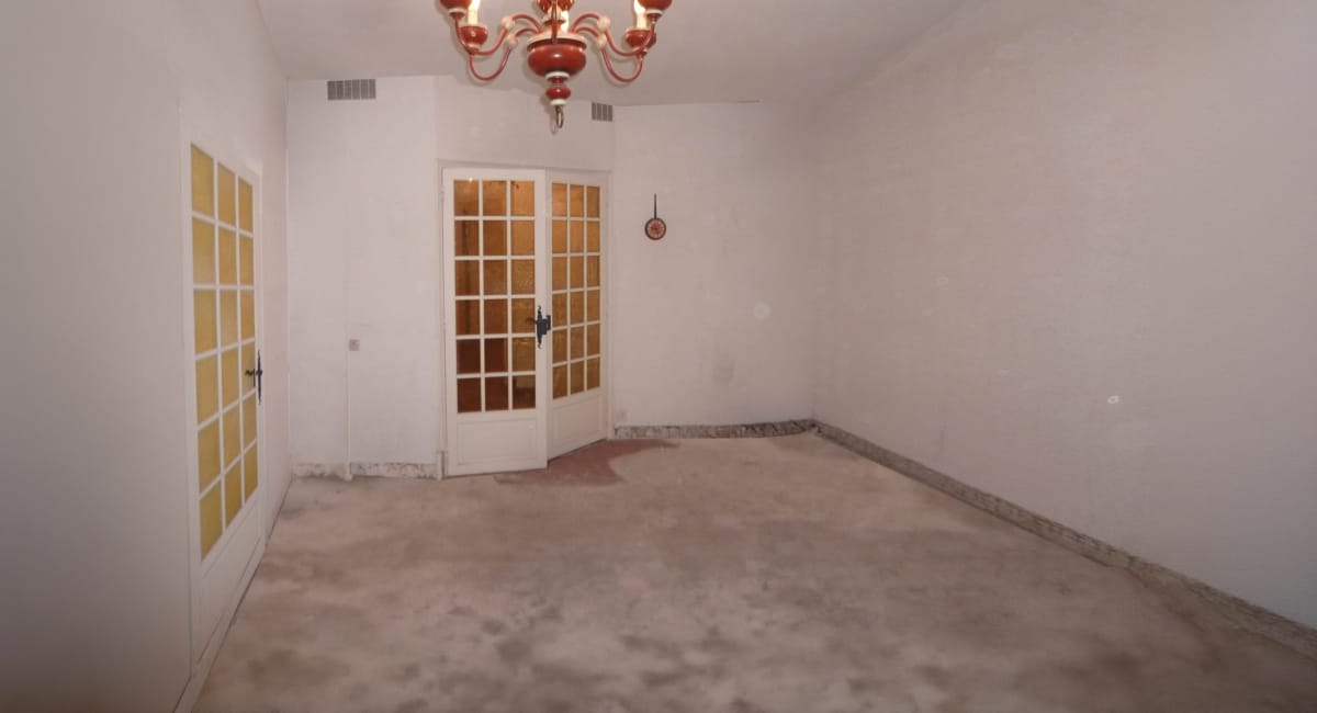 Une pièce vide et lumineuse avec des portes doubles et un lustre décoratif.