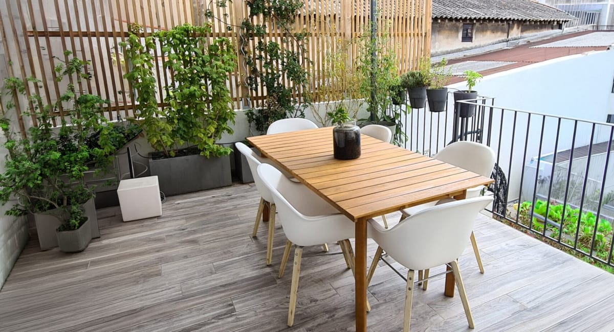 Une terrasse urbaine agréable avec une table, des chaises et des plantes vertes.