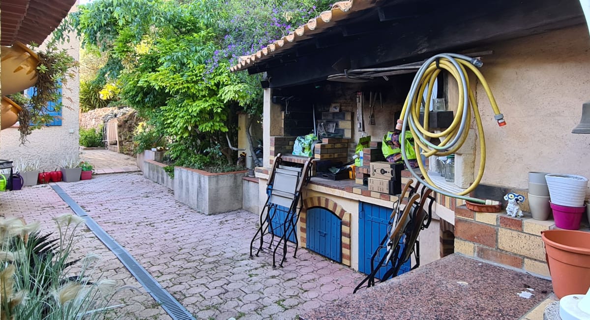 Une cuisine d'extérieur rustique avec un barbecue et des accessoires dans un jardin.