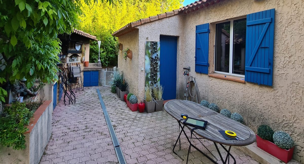 Un patio extérieur avec une table, des plantes et une maison de campagne.