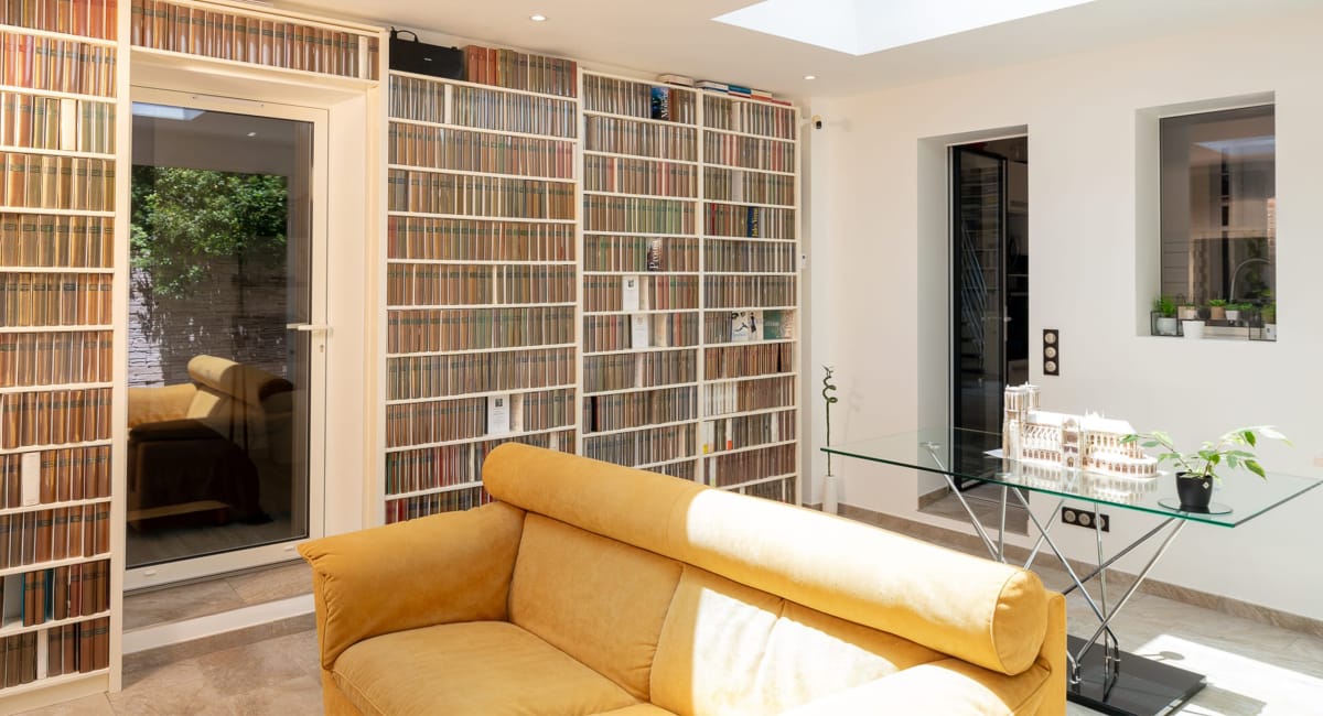 Une bibliothèque murale remplie de livres et de vinyles, un intérieur chaleureux et accueillant.