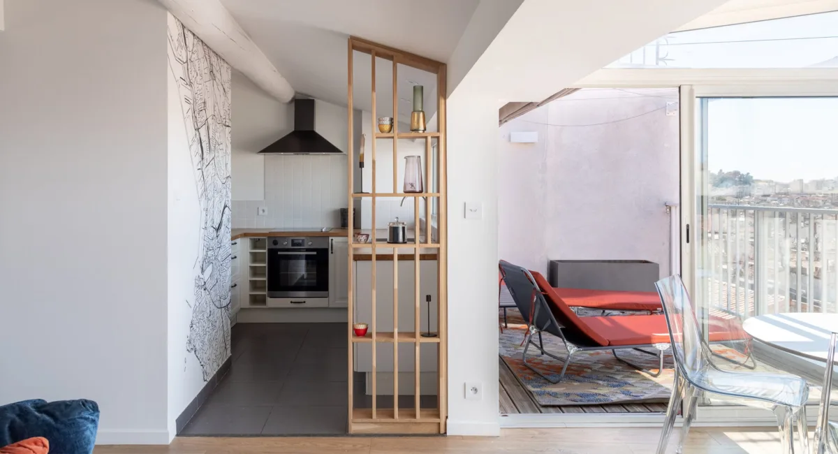 Cuisine moderne et espace de vie ouvert avec accès à un balcon lumineux.