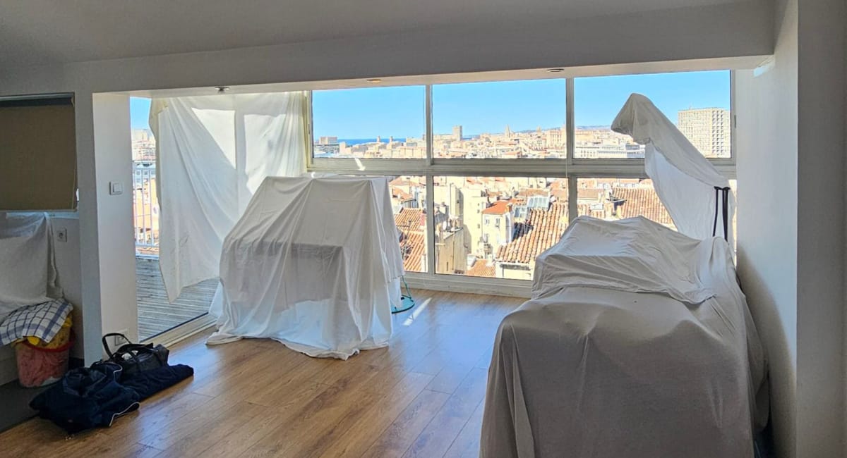 Intérieur d'un appartement avec des tentes blanches devant une vue sur la ville.