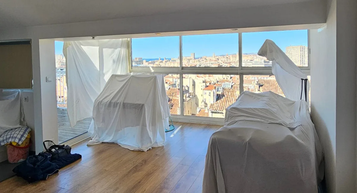 Intérieur d'un appartement avec des tentes blanches devant une vue sur la ville.