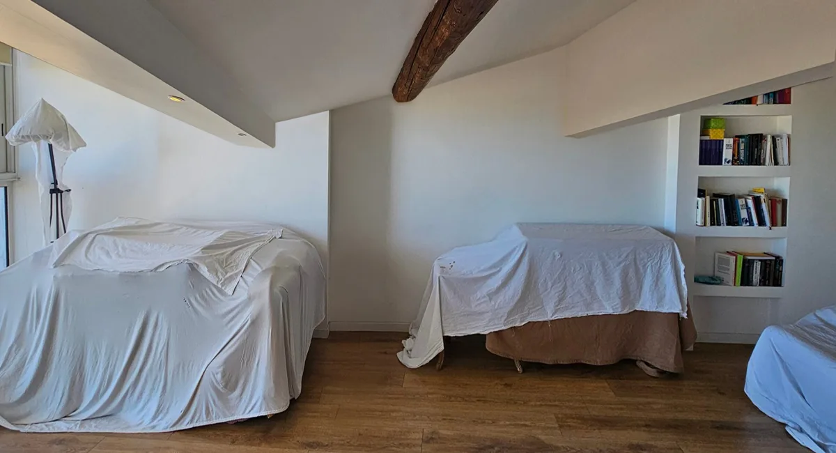 Vue d'un intérieur avec deux voitures recouvertes de draps, dans un espace de rangement.