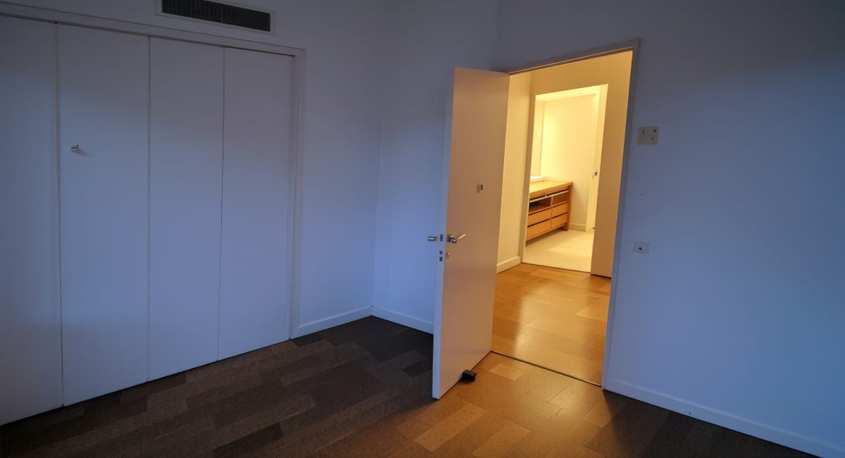 Une chambre avec un grand placard blanc et un passage vers une salle de bains.