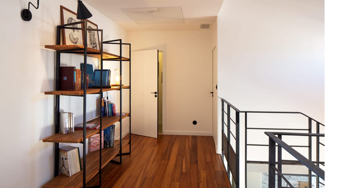 Une étagère en métal et des livres sur une mezzanine d'un intérieur moderne.