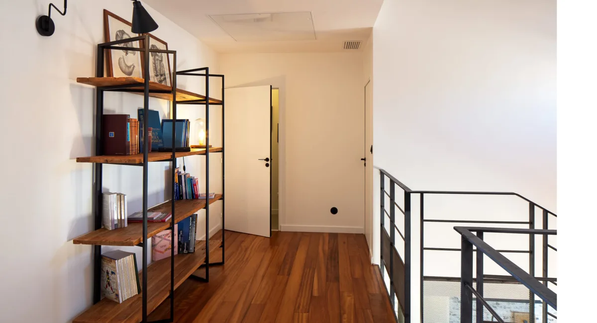 Une étagère en métal et des livres sur une mezzanine d'un intérieur moderne.
