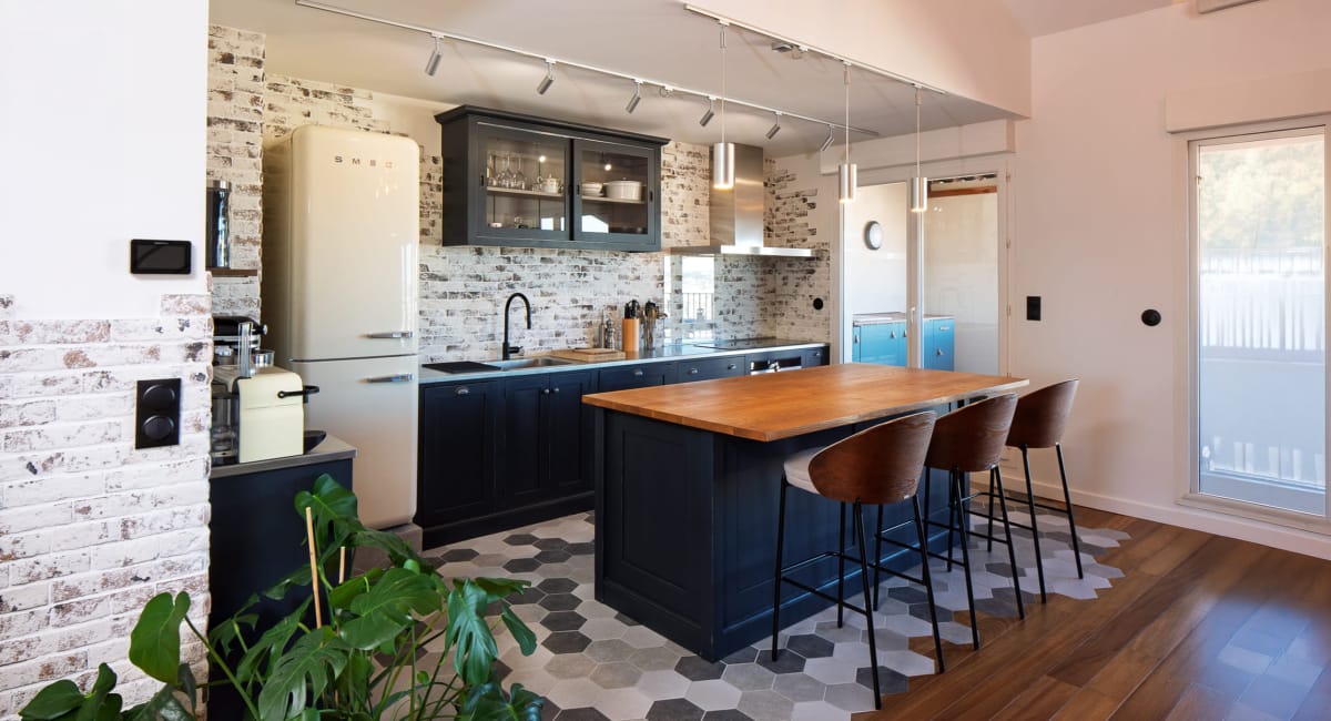 Cuisine moderne et chaleureuse avec îlot central et murs en briques apparentes.