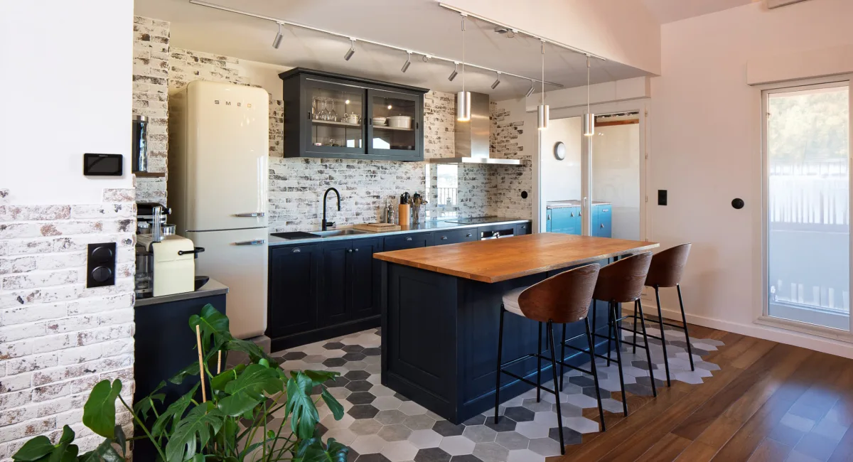 Cuisine moderne et chaleureuse avec îlot central et murs en briques apparentes.
